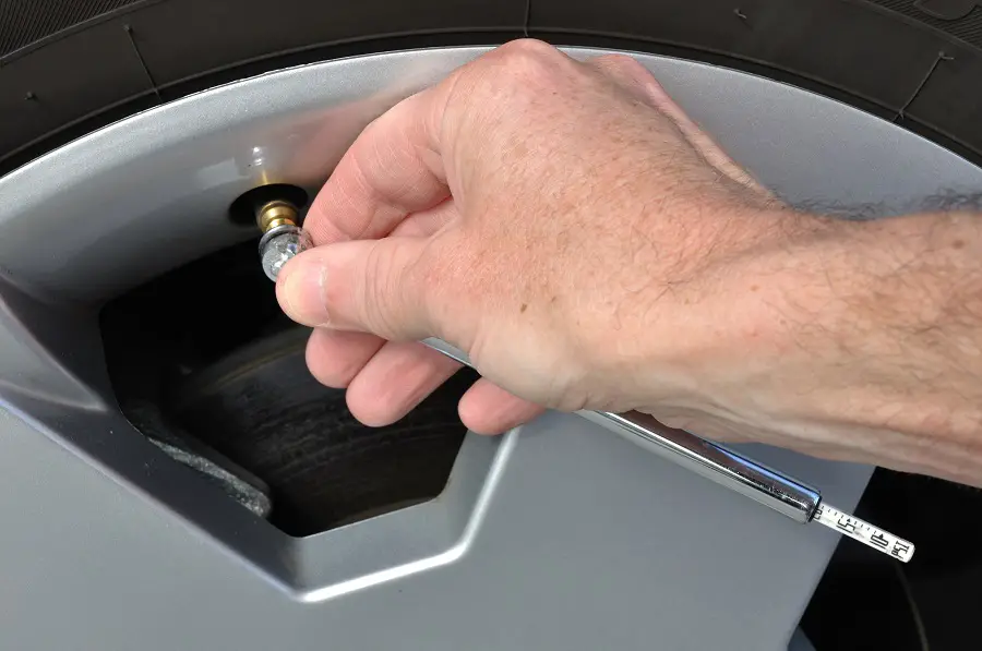 checking tire pressure with a stick gauge