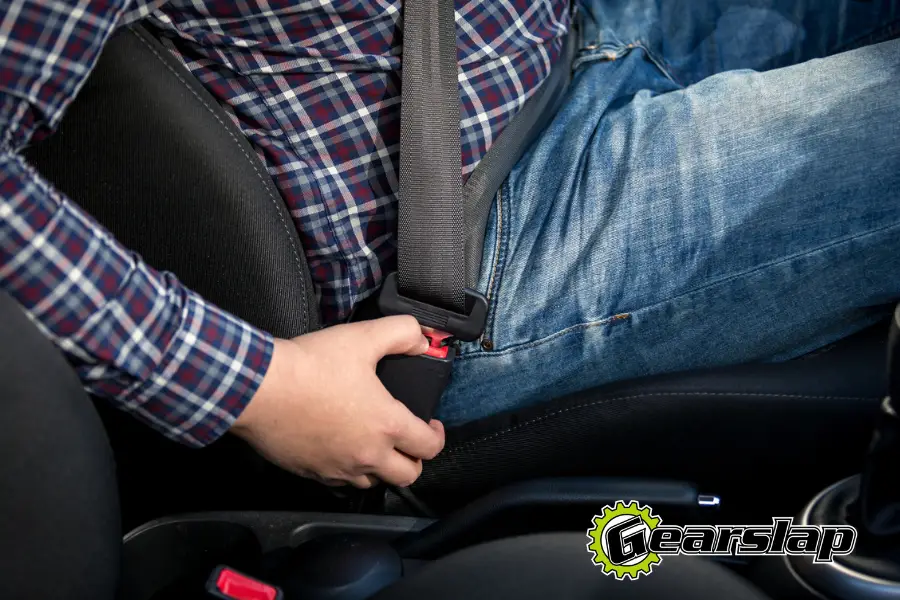Man unbuckling seat belt in car