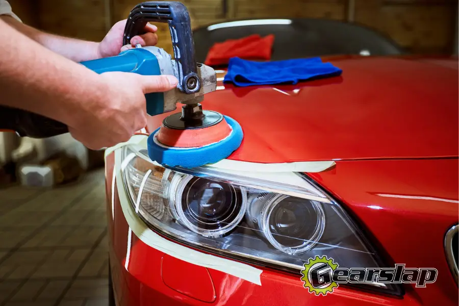 Man waxing a red car headlights and windows