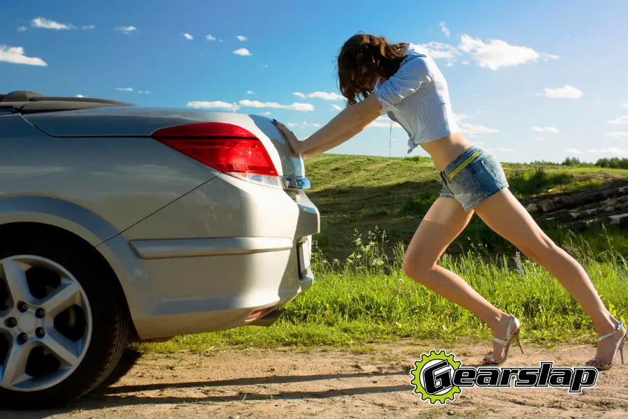 girl pushing car broken down out of gas