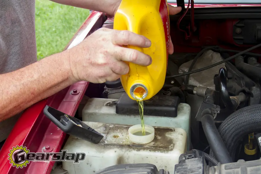 man adding antifreeze to coolant reservoir with water 900x600 1